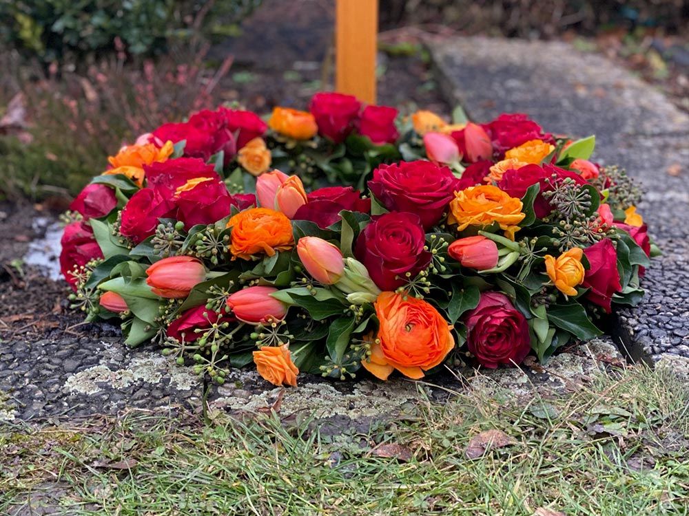 Gaertnerei Vietzen Ulm Trauerfloristik Blumen am Grab für Urnenbestattung rot/orange